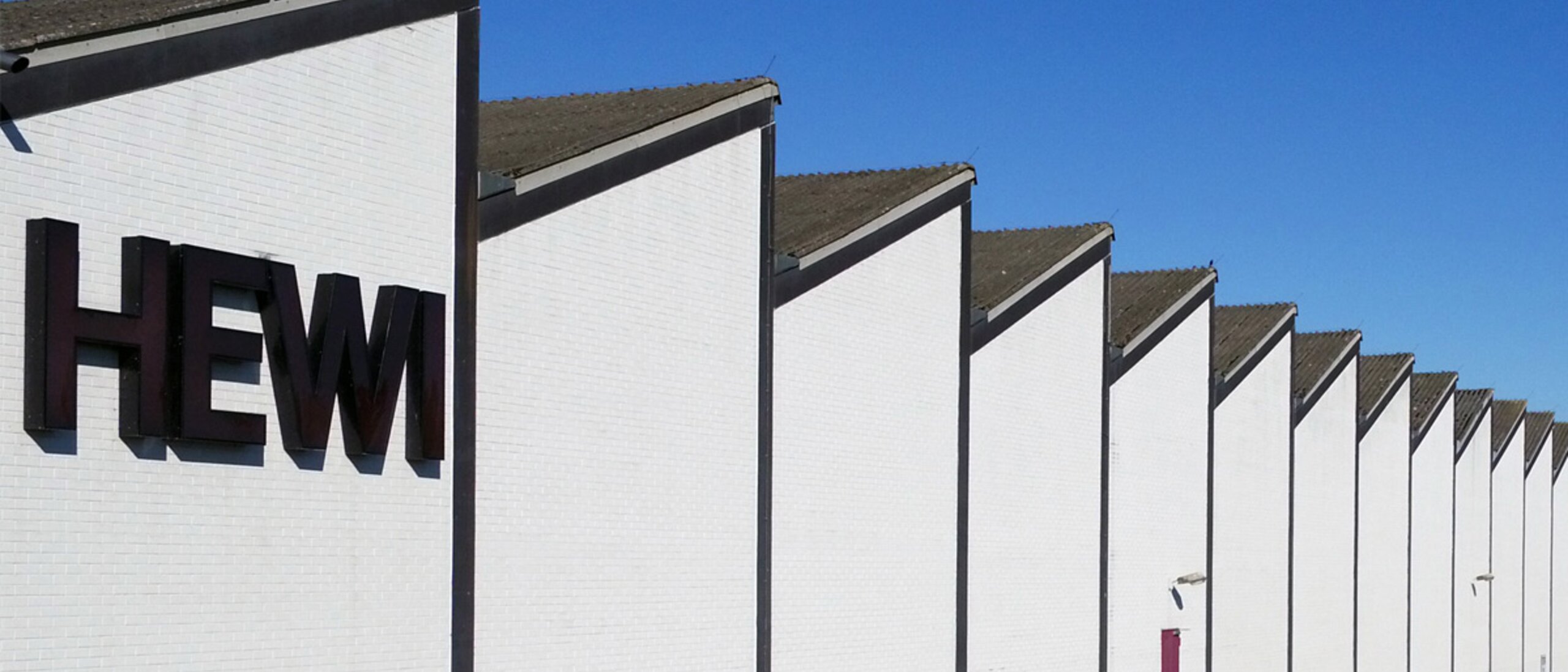 HEWI factory with white façade, "HEWI" lettering and shed roof